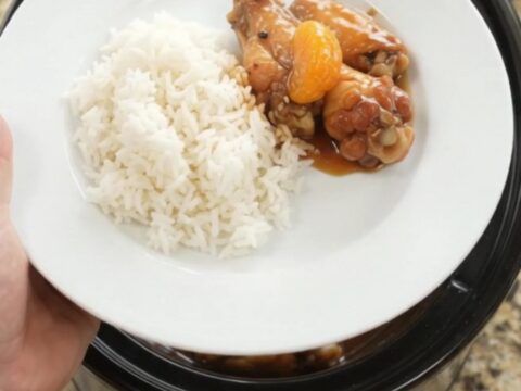 Sticky teriyaki chicken wings with mandarin oranges in a slow cooker, garnished with sesame seeds