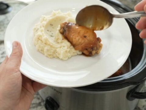 Sticky mandarin bourbon glazed chicken wings in a slow cooker, coated in glossy sauce with orange segments
