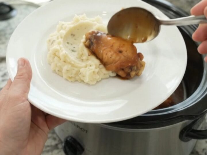 Sticky mandarin bourbon glazed chicken wings in a slow cooker, coated in glossy sauce with orange segments