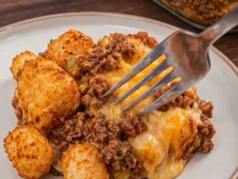 A close-up of a cheesy sloppy joe tater tot casserole with molten cheese and crispy tots.