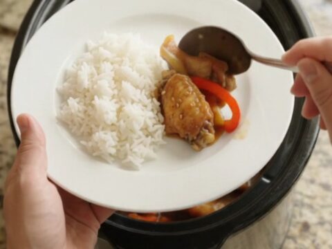 Slow cooker teriyaki chicken wings with bell peppers and sesame seeds in a black crockpot