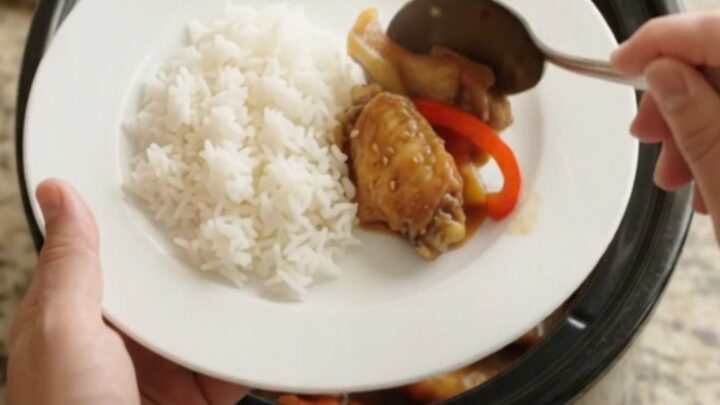 Slow cooker teriyaki chicken wings with bell peppers and sesame seeds in a black crockpot