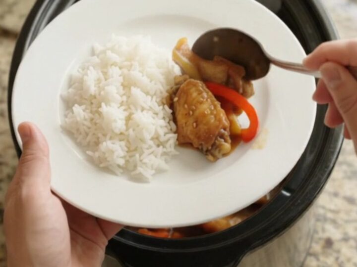 Slow cooker teriyaki chicken wings with bell peppers and sesame seeds in a black crockpot