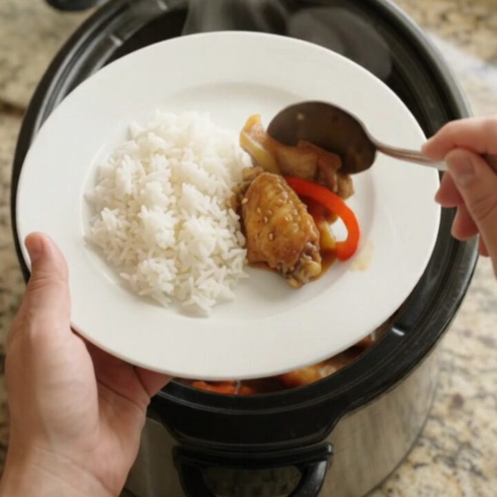 Slow cooker teriyaki chicken wings with bell peppers and sesame seeds in a black crockpot