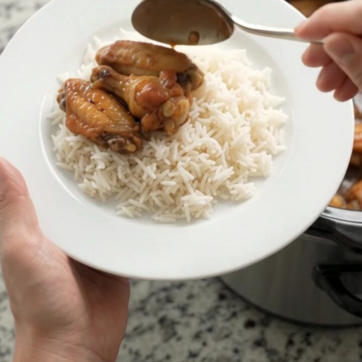 Sticky honey soy chicken wings in a slow cooker with garlic cloves and scallions