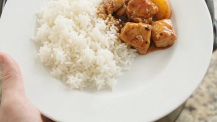 A slow cooker filled with glazed chicken and peach slices in hickory BBQ sauce