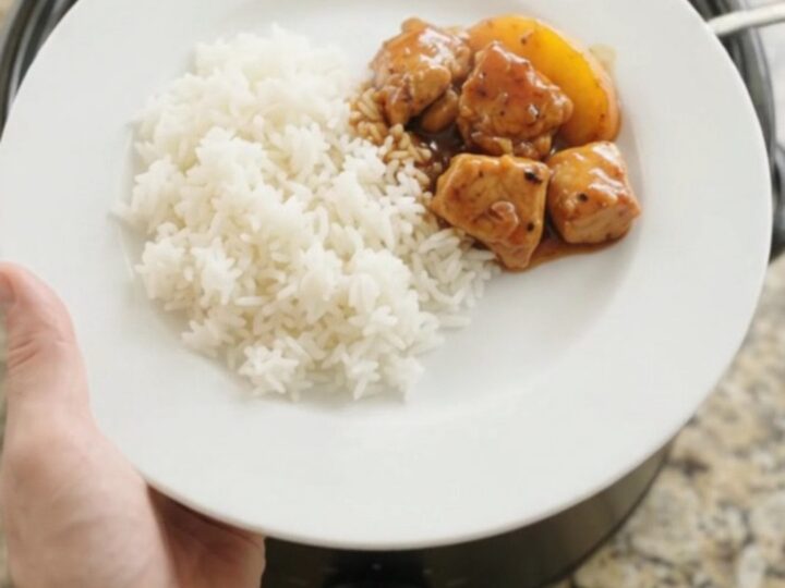 A slow cooker filled with glazed chicken and peach slices in hickory BBQ sauce