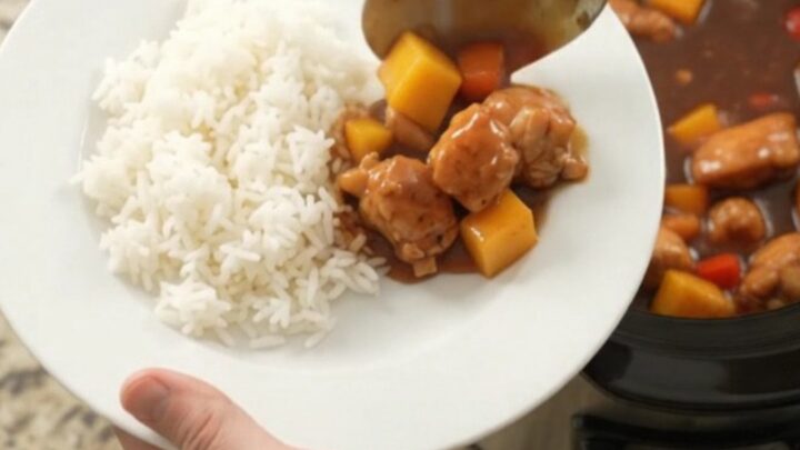 A bowl of mango hickory BBQ chicken bites with rice, garnished with fresh herbs