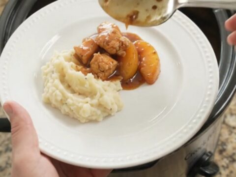 Glazed chicken bites and peach slices in a bubbling bourbon molasses sauce in a slow cooker