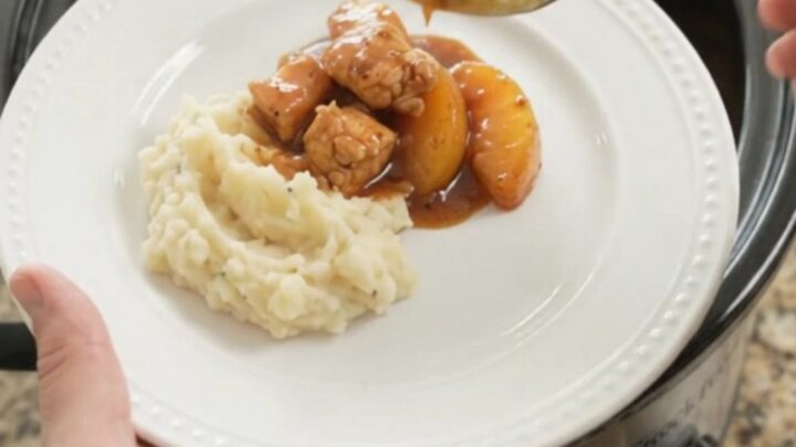 Glazed chicken bites and peach slices in a bubbling bourbon molasses sauce in a slow cooker