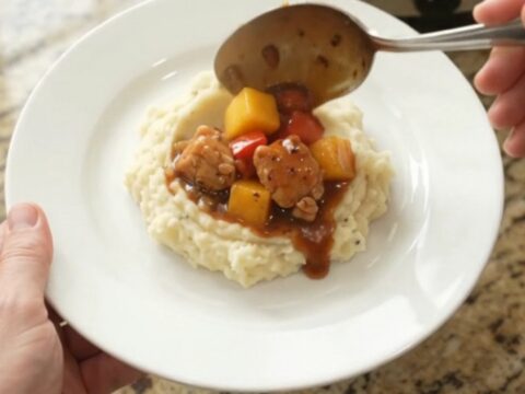 Slow cooker filled with glazed chicken, mango, and red peppers in a bourbon molasses sauce