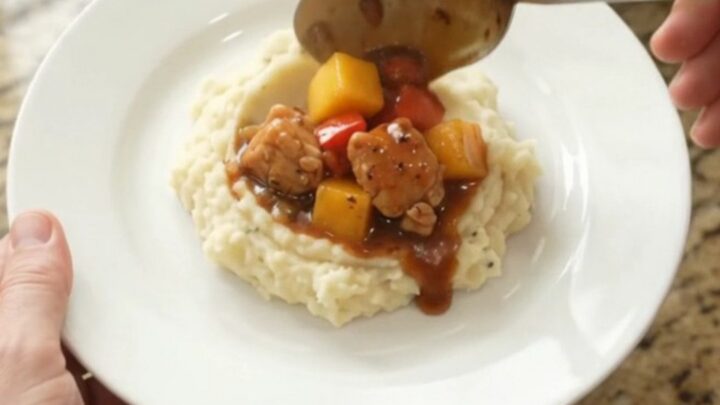 Slow cooker filled with glazed chicken, mango, and red peppers in a bourbon molasses sauce