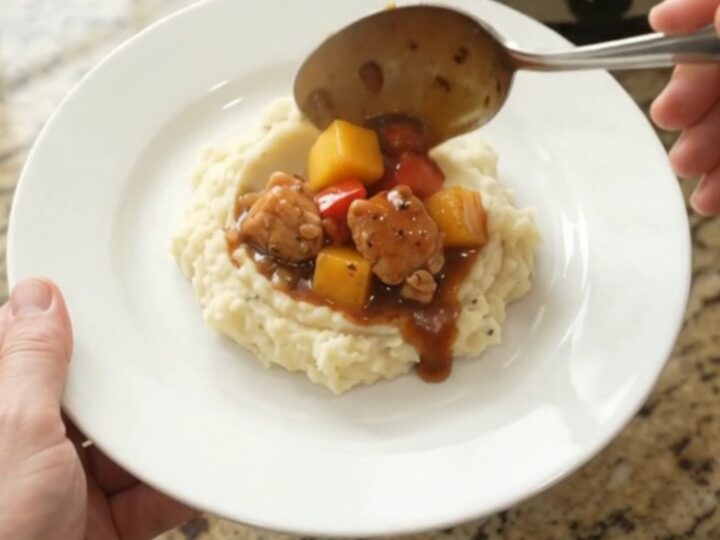 Slow cooker filled with glazed chicken, mango, and red peppers in a bourbon molasses sauce