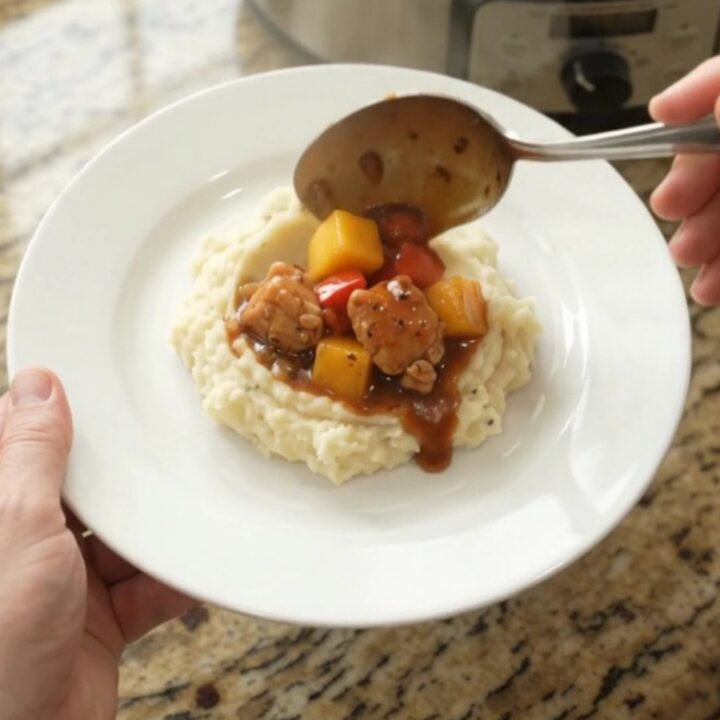 Slow cooker filled with glazed chicken, mango, and red peppers in a bourbon molasses sauce