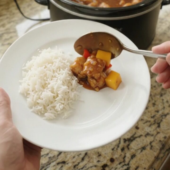 Crockpot mango honey soy chicken bites in a slow cooker, glistening with sticky amber sauce and topped with mango cubes