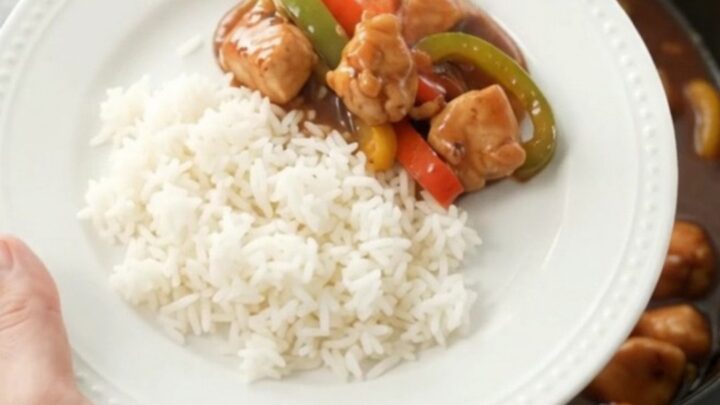 Slow-cooker hickory BBQ chicken bites with bell peppers in a black crockpot, coated in thick glaze.