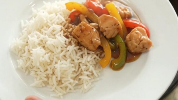 Slow cooker honey soy chicken bites with bell peppers and onions, glazed and steaming in the crock