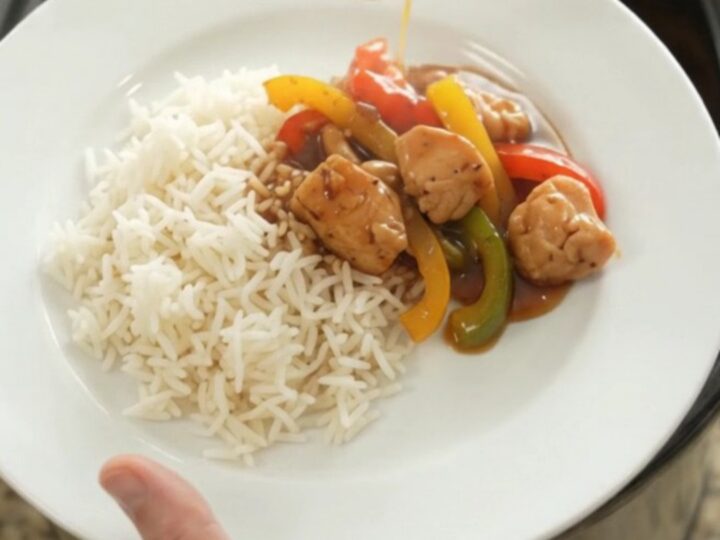 Slow cooker honey soy chicken bites with bell peppers and onions, glazed and steaming in the crock