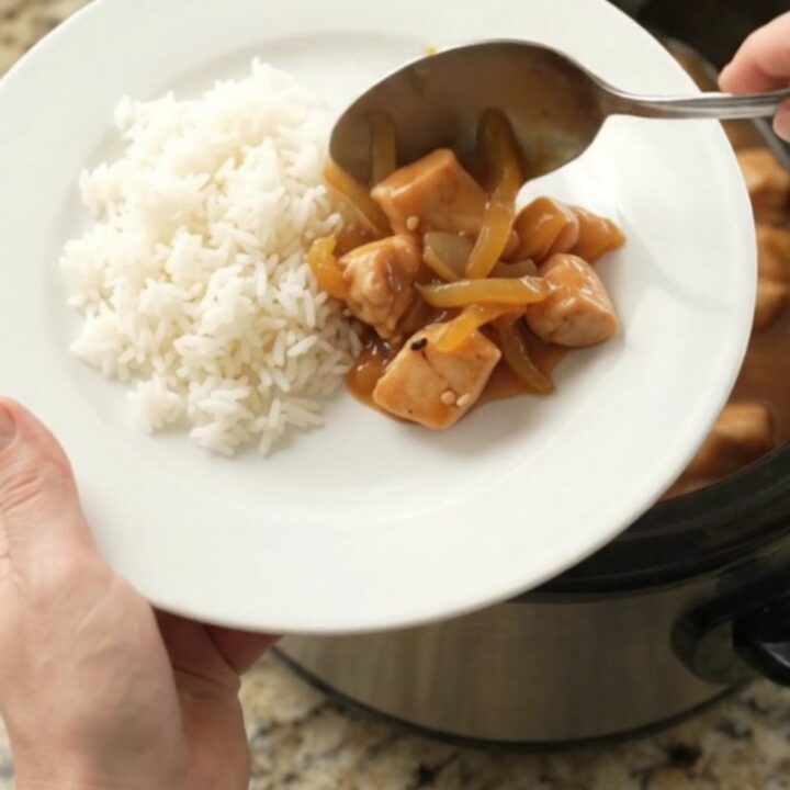 Glossy apricot teriyaki chicken bites in a slow cooker with sesame seeds and sauce