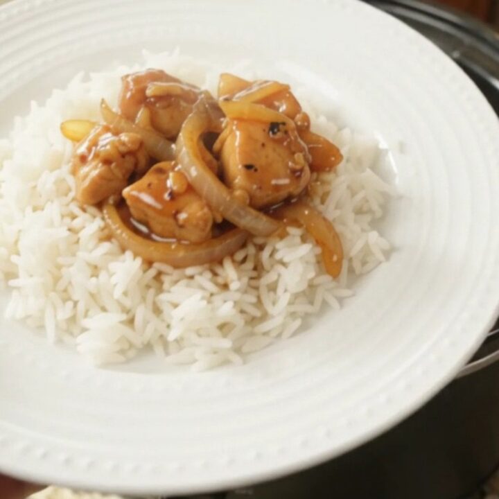 Glazed chicken bites and caramelized onions in a slow cooker with a glossy honey-soy sauce.