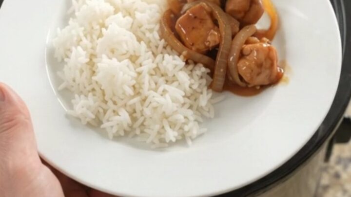 Crockpot full of glazed chicken bites and caramelized onions with steam rising