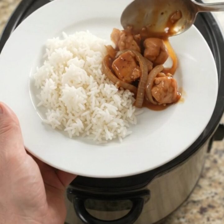 Crockpot full of glazed chicken bites and caramelized onions with steam rising
