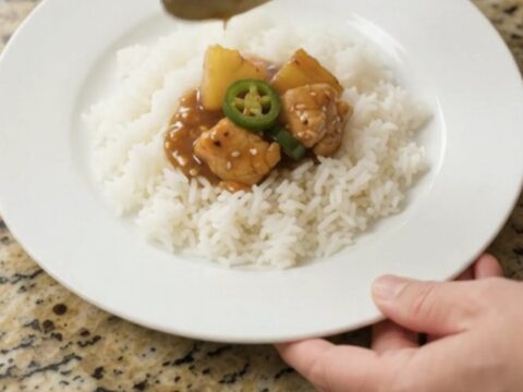 Glazed teriyaki chicken bites with pineapple and jalapeños in a slow cooker, topped with sesame seeds
