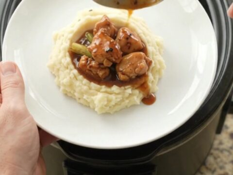 Glazed chicken bites in a slow cooker with ginger and scallions, glossy bourbon sauce