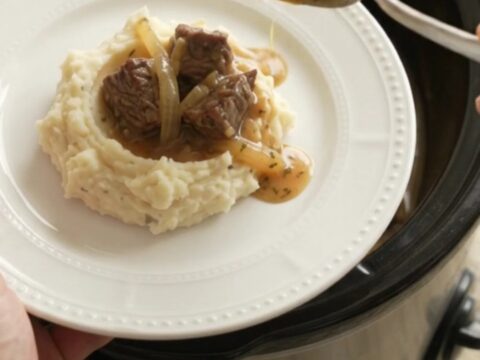 Bubbling crockpot of beef bites and onions in golden au jus
