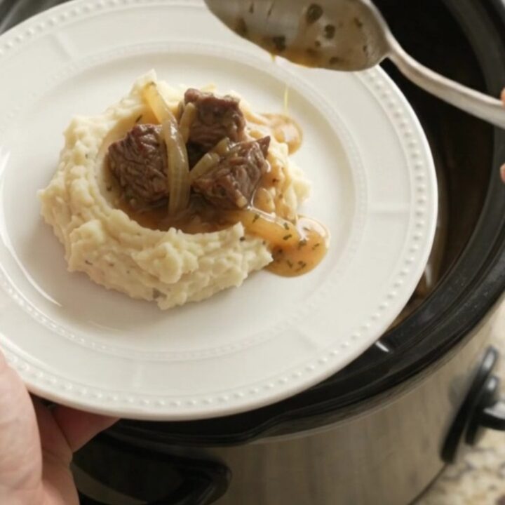 Bubbling crockpot of beef bites and onions in golden au jus