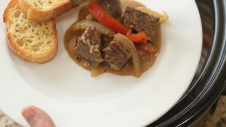 Slow cooker beef with creamy Gruyère sauce and peppers in a black crockpot