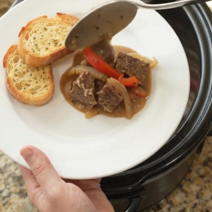 Slow cooker beef with creamy Gruyère sauce and peppers in a black crockpot