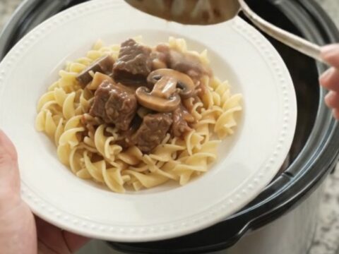 A slow cooker filled with sour cream broccoli beef bites, topped with creamy gravy.