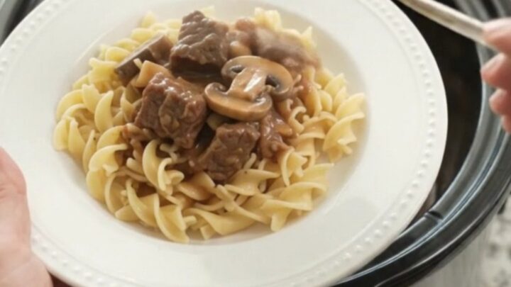 A slow cooker filled with sour cream broccoli beef bites, topped with creamy gravy.