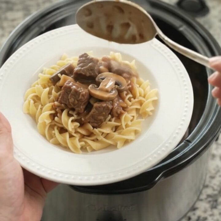 A slow cooker filled with sour cream broccoli beef bites, topped with creamy gravy.