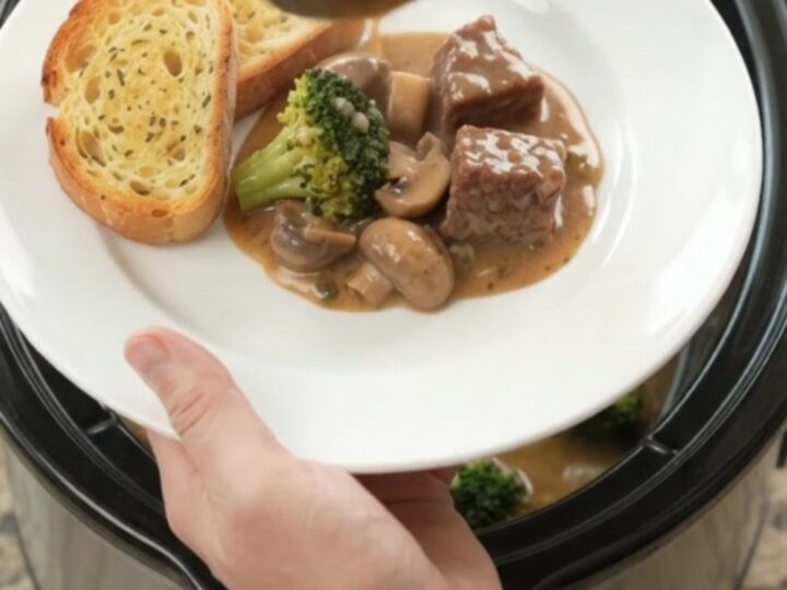 Slow cooker filled with creamy Gruyère sauce, beef, broccoli, and mushrooms