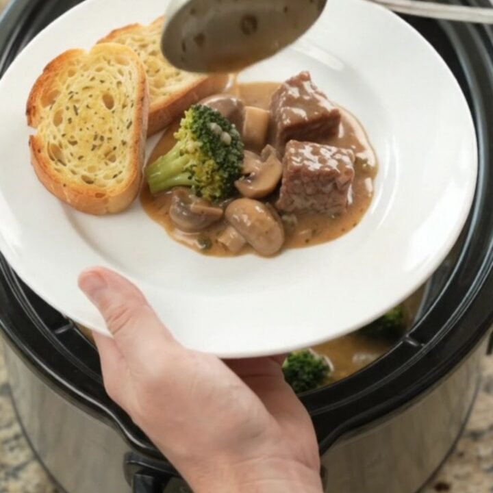 Slow cooker filled with creamy Gruyère sauce, beef, broccoli, and mushrooms