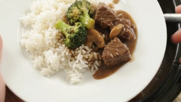 Crockpot Bourbon Gravy Broccoli Beef Bites in a black slow cooker, with steam rising