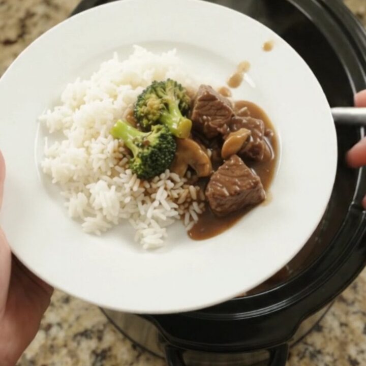 Crockpot Bourbon Gravy Broccoli Beef Bites in a black slow cooker, with steam rising