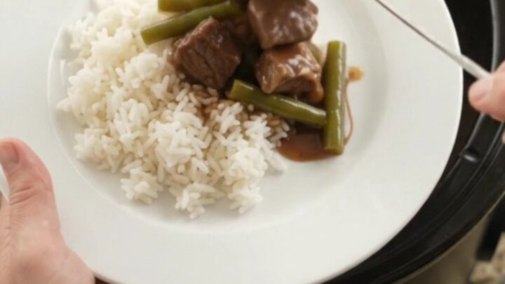 Slow cooker filled with beef, green beans, and potatoes in bourbon gravy