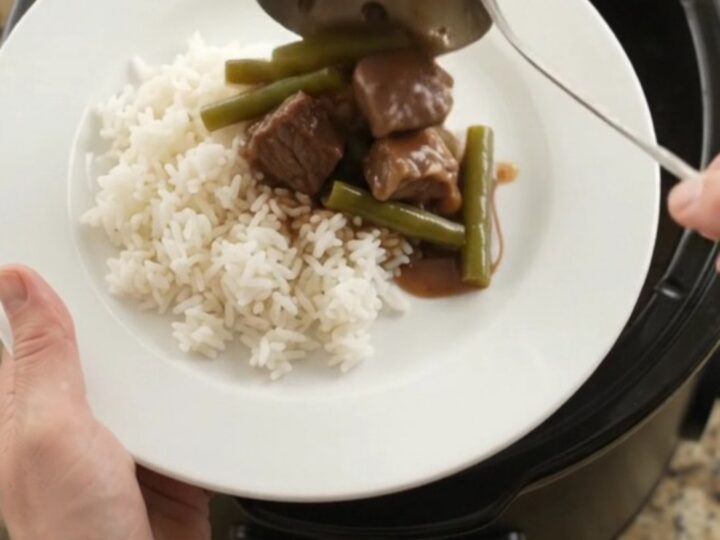 Slow cooker filled with beef, green beans, and potatoes in bourbon gravy