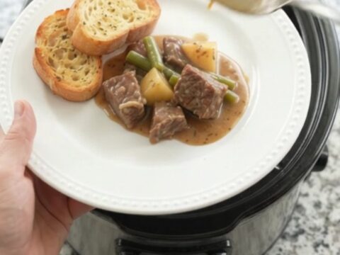 Slow cooker filled with creamy beef, green beans, and potatoes in a rich cheese sauce