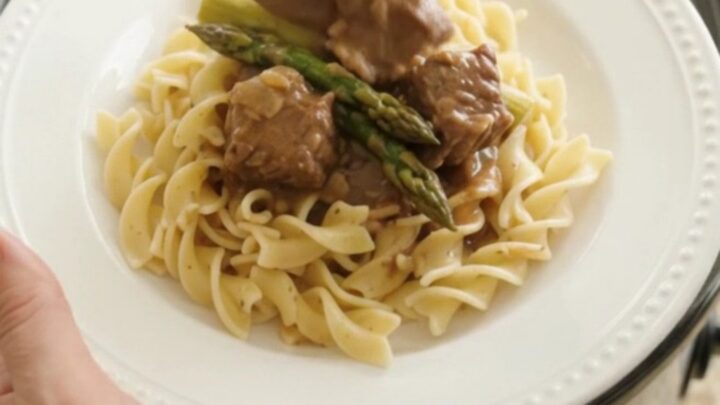 Slow cooker filled with beef, asparagus, and sour cream gravy