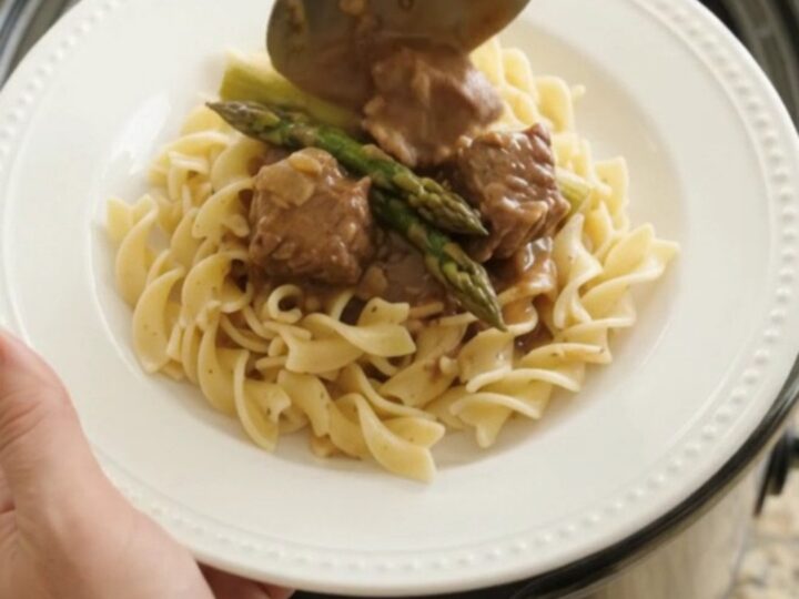 Slow cooker filled with beef, asparagus, and sour cream gravy
