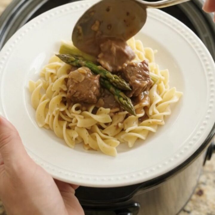 Slow cooker filled with beef, asparagus, and sour cream gravy