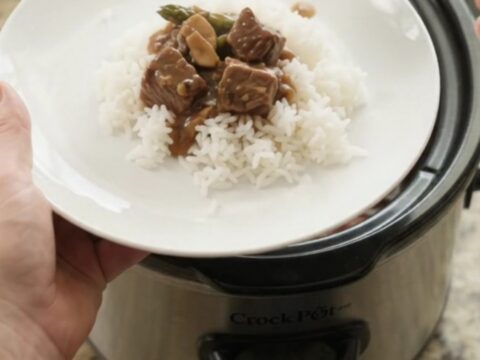 Slow cooker bourbon gravy asparagus beef bites in a glossy black crockpot