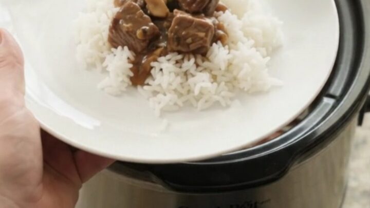 Slow cooker bourbon gravy asparagus beef bites in a glossy black crockpot