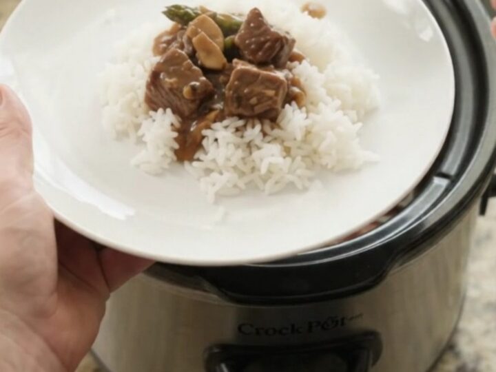 Slow cooker bourbon gravy asparagus beef bites in a glossy black crockpot