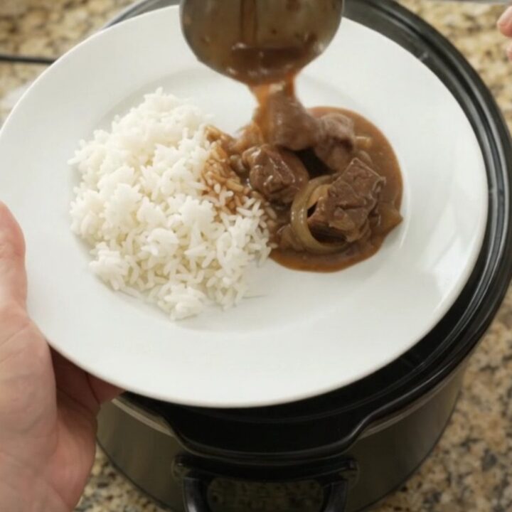 Slow cooker filled with tender sirloin tips and onions in rich bourbon gravy