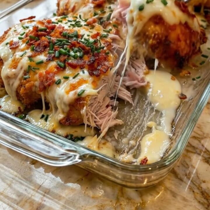A golden cheesy bacon ranch chicken breast with melted cheese and crispy bacon in a casserole dish.